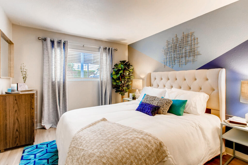 bedroom with wood-style flooring, lamp lights, plant decor, and window