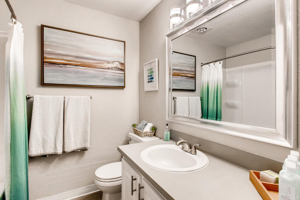 bathroom with single sink, wall mirror, toilet, and wood-style flooring
