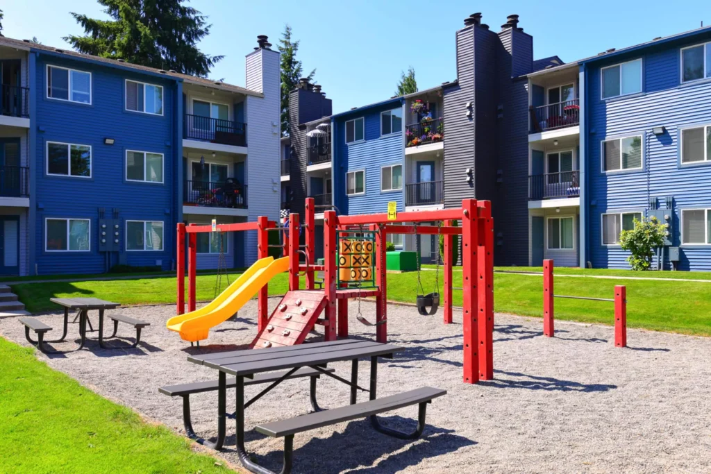a children's playground with swings, a slide, and climbing bars