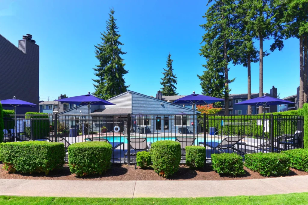 Pool with deck furniture and large trees around